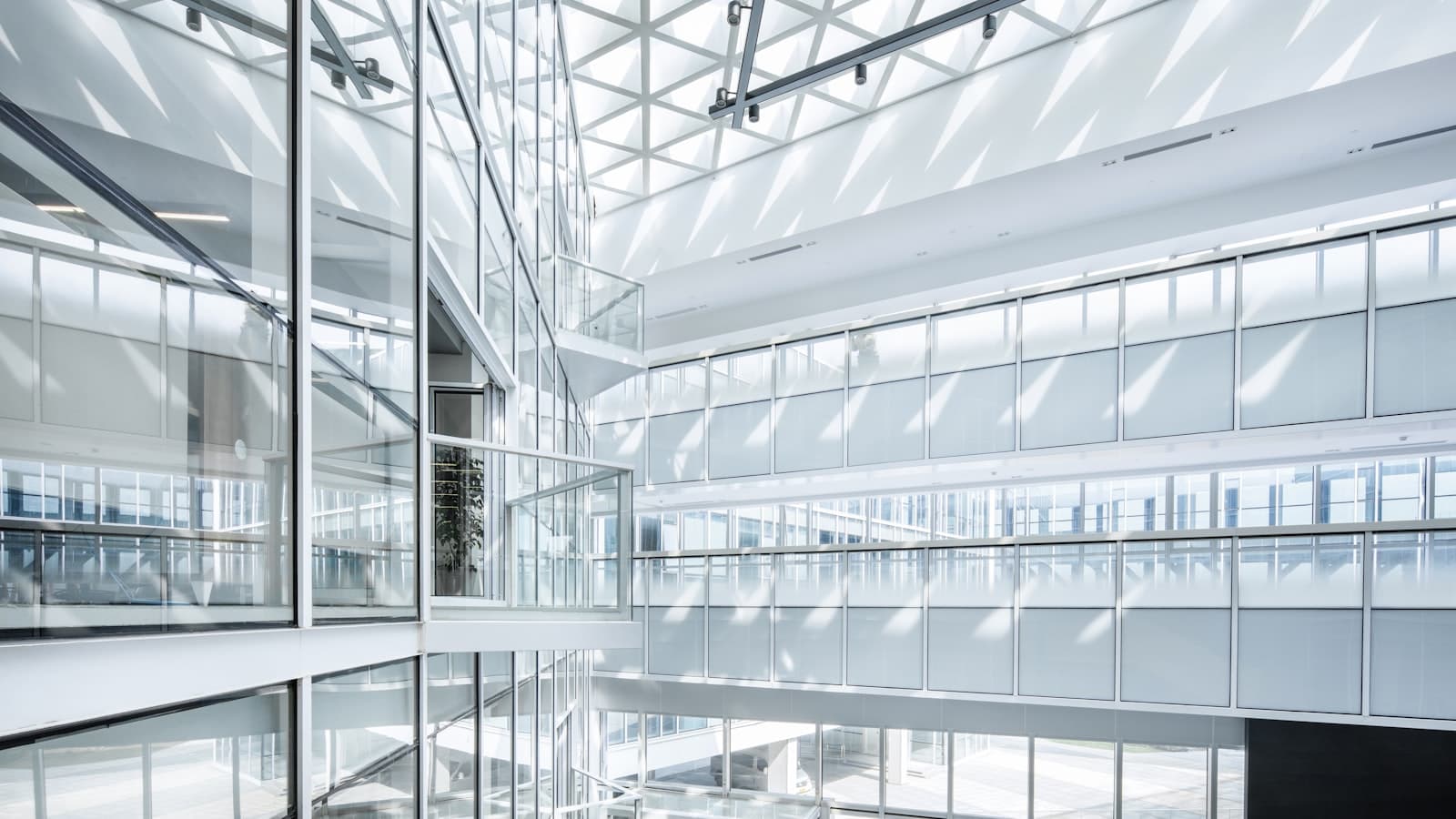 Bright interior of a modern glass atrium with steel framing and multiple floor levels