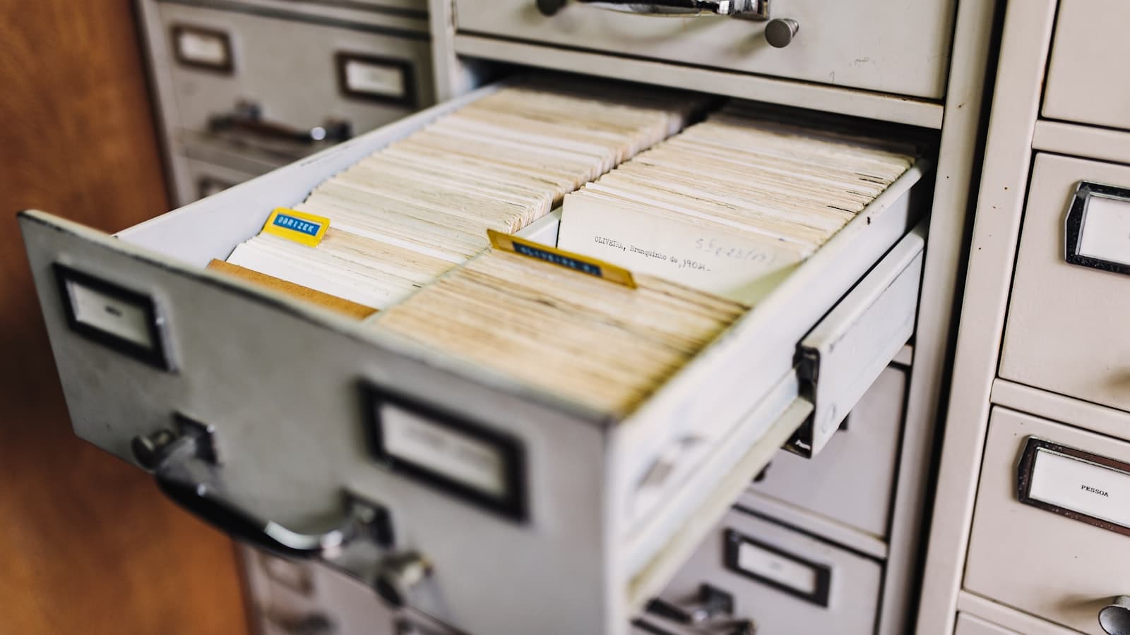 An open filing cabinet drawer packed with paper client record cards