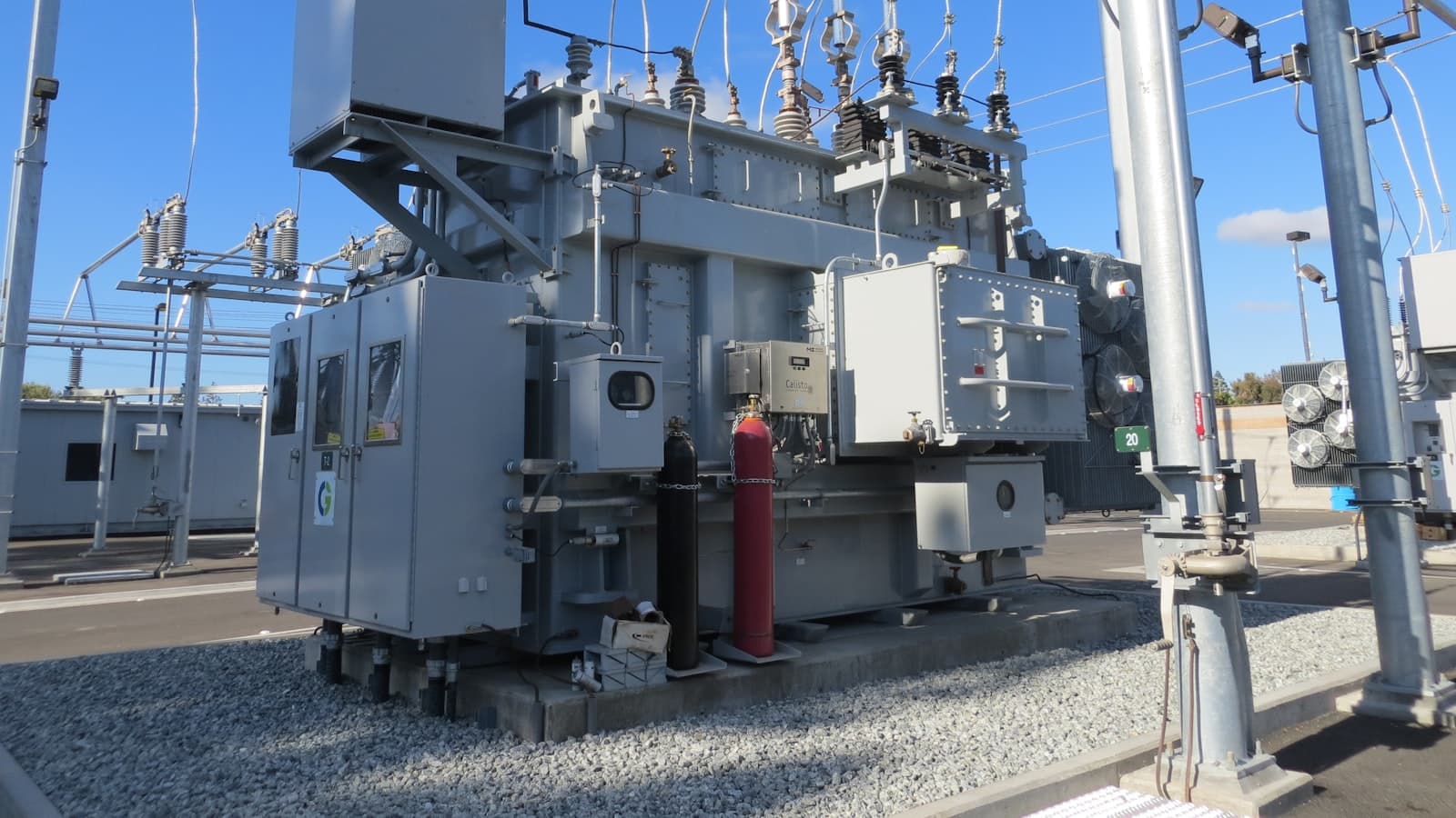 An outdoor electrical substation transformer with insulators and cabling under a blue sky