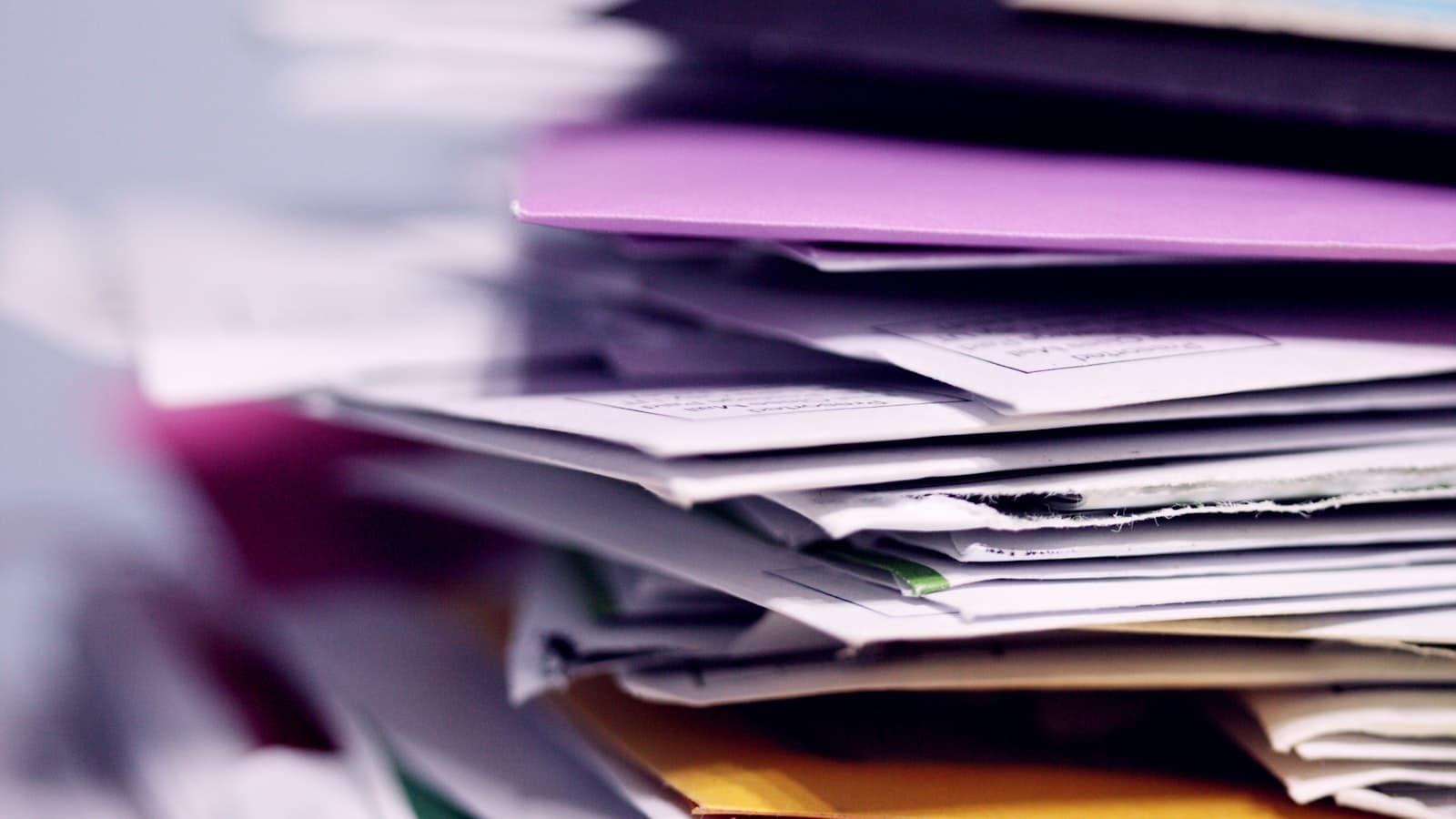 Close-up of a messy stack of papers and documents with a purple folder on top