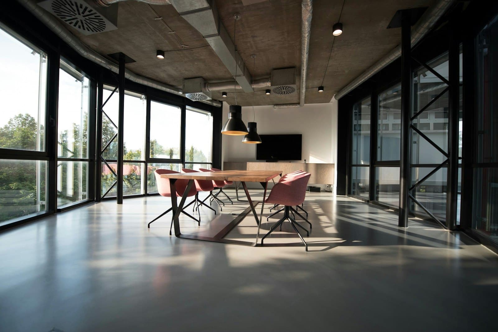 An empty meeting room with a long table and glass partitions